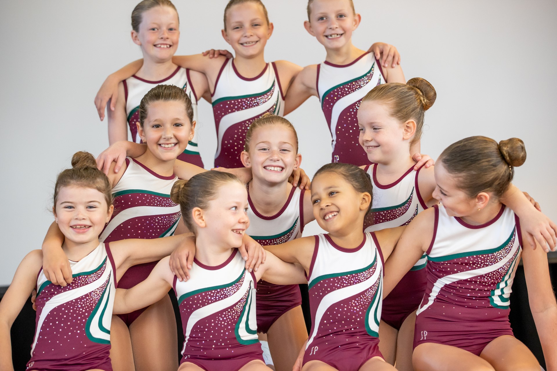 Group of students in matching sports aerobics uniforms posing together indoors.